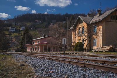 Railroad tracks by buildings in town against sky