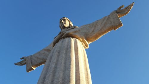 Low angle view of cristo rei statue against clear blue sky