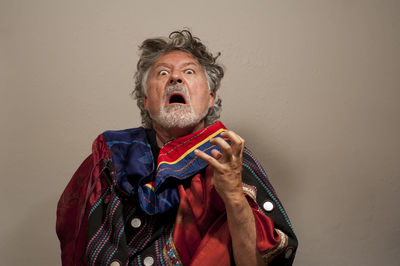 Portrait of man holding mask against wall