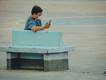 Full length of boy sitting on mobile phone