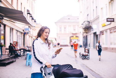 Woman on street amidst buildings in city