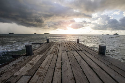 Wooden pier over sea against sky during sunset