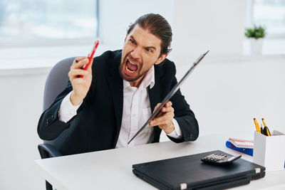 Businessman shouting on phone at office