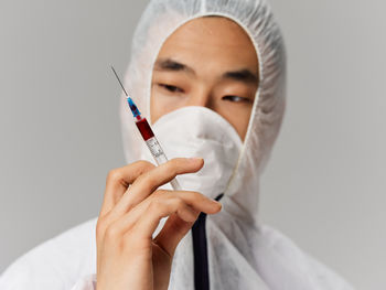 Midsection of doctor holding syringe against white background