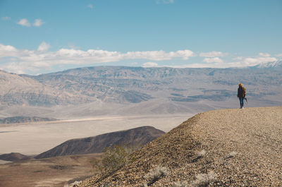 Rear view of woman standing on mountain against sky