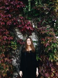 Portrait of smiling young woman standing against trees