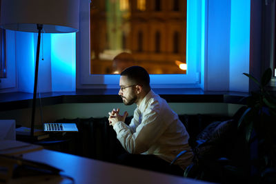 Thoughtful young businessman look at laptop monitor analyze financial report and sales late at night