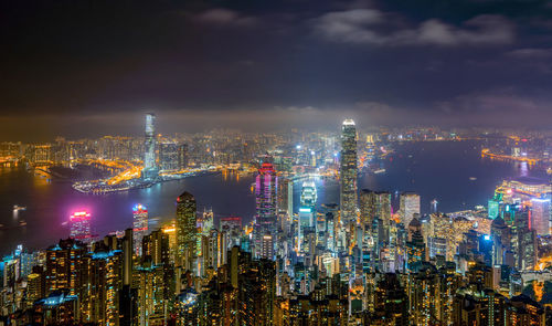 Illuminated cityscape and victoria harbour at night