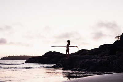 Beautiful, fit woman with surfboard on beach in tofino