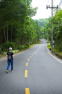 Man standing on road amidst trees