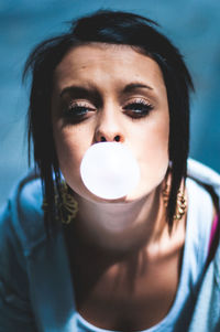 Close-up portrait of young woman blowing bubble gum
