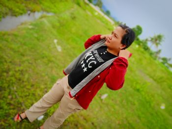 Rear view of boy holding red umbrella on field