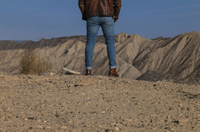 Rear view of adult man legs standing on cliff in tabernas desert, almeria, spain