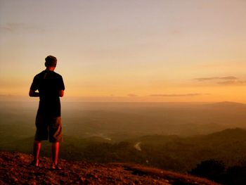 Rear view of man standing on landscape against sky