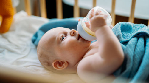 Cute baby drinking milk in crib