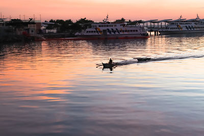 Silhouette people in boat against sky during sunset