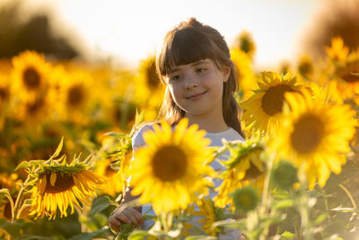 Portrait of girl with yellow flowers in field