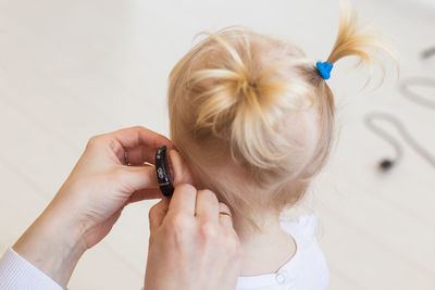 Close-up of mother adjusting hearing aid of daughter