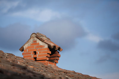 Low angle view of chimney on roof against sky