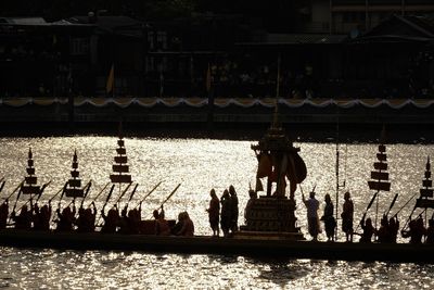 People by lake against buildings