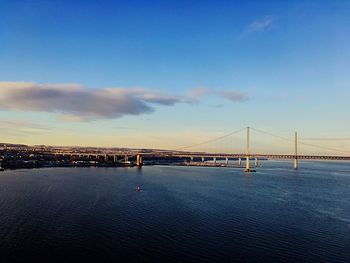 Suspension bridge over sea against cloudy sky