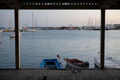 Sailboats moored on pier by sea against sky