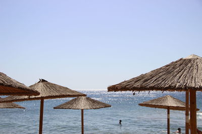 Lounge chairs on beach by sea against clear sky