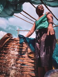 Low angle view of man looking away while standing by basket against sky