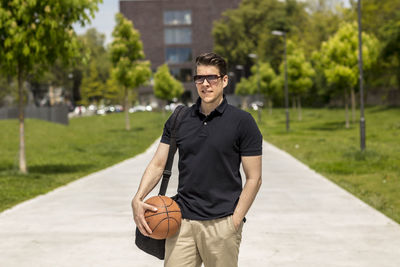 Close-up of mature man holding basketball while standing outdoors