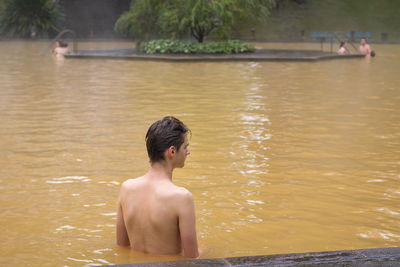 Rear view of shirtless man in lake