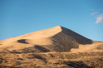 Low angle view of desert against clear blue sky