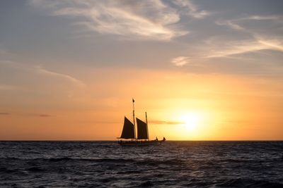 Sailboat sailing on sea against sky during sunset