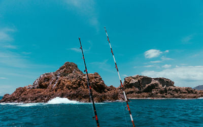 Rock formation in sea against blue sky