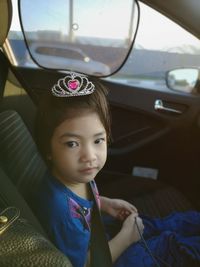 Portrait of cute girl wearing crown sitting in car
