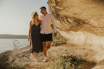 Couple walking on rock formation during sunset