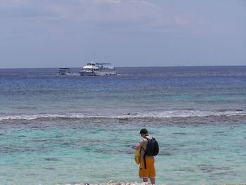 Rear view of man standing at beach against sky