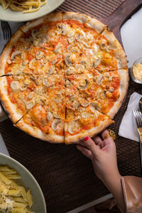 Cropped image of woman holding pizza on table