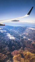 Airplane flying over snowcapped mountains against sky