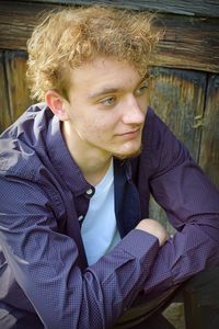 High angle view of teenage boy looking away while sitting on seat