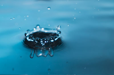 Close-up of drop falling on blue water