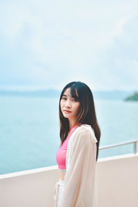 Young woman looking away against sea