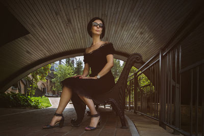 A pretty charming middle-aged woman in a black dress and sunglasses strolls through the city park
