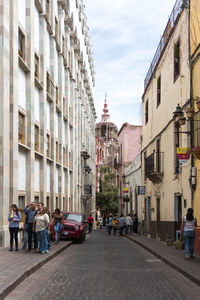 People on street in city against sky