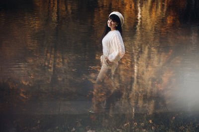 Portrait of young woman standing by lake