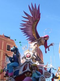 Low angle view of statue against building against clear blue sky