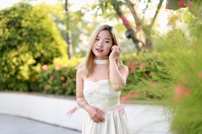 Portrait of young woman standing against plants
