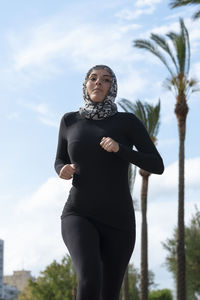 Portrait of young woman standing against sky