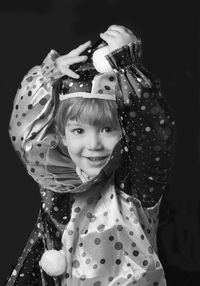 Portrait of smiling boy wearing clown costume against black background