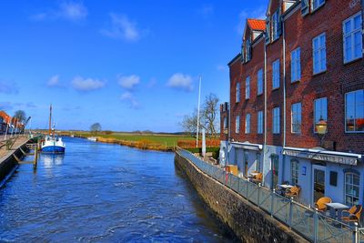 Canal amidst buildings in city against sky