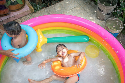 High angle view of siblings with parent in wading pool